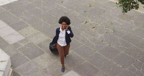 Businesswoman Walking with Luggage Talking on Smartphone on City Street