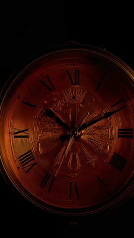 Ticking second hand advancing minute hand on amber-lit vintage clock embossed dial — vertical clip