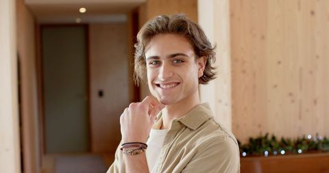 Smiling man in rustic wood-paneled hallway with garland lights