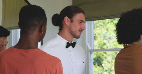 Groom adjusting bow tie with friends before wedding ceremony