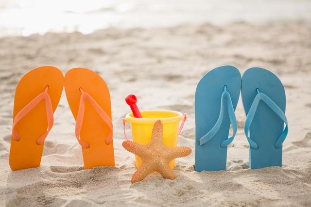 Flip flops, bucket and starfish in sand at beach
