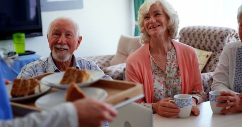 Seniors enjoying breakfast at nursing home with caring nurse