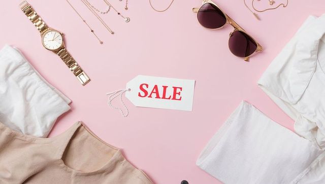 Fashion sale flatlay featuring white sale tag, sunglasses, gold jewelry and neutral tops
