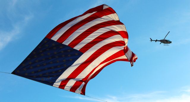 Large American Flag Flying with Helicopter in Clear Blue Sky - Download Free Stock Photos Pikwizard.com
