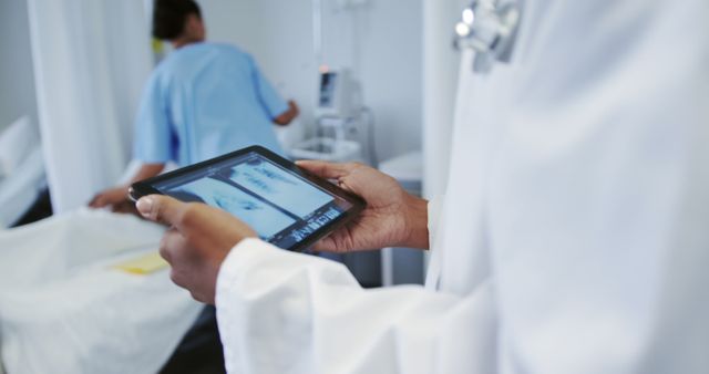Doctor reviews digital x-ray on tablet in hospital, with copy space. Medical professional analyzes patient's imaging in clinical setting.