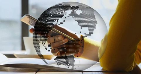 Right hand using smartphone over open book with dotted globe overlay for global learning