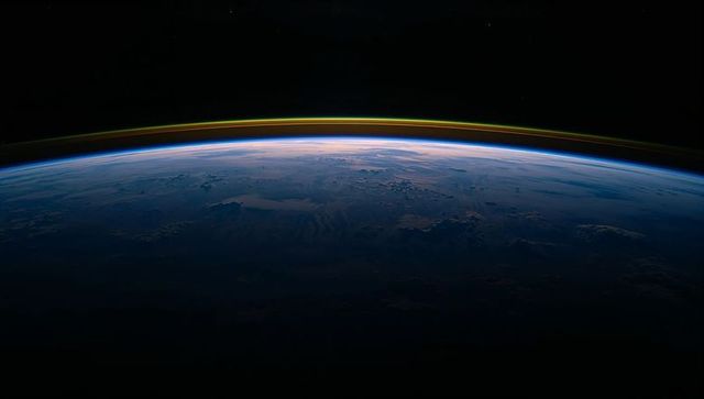 Curved earth limb glowing at terminator from orbit with vivid airglow and twilight horizon