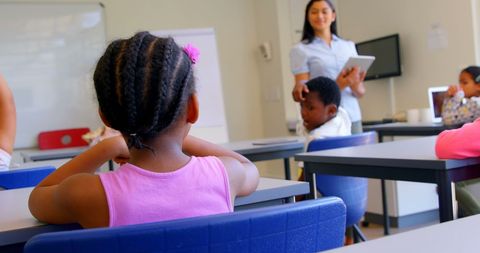 Diverse students learning with teacher using tablet in classroom