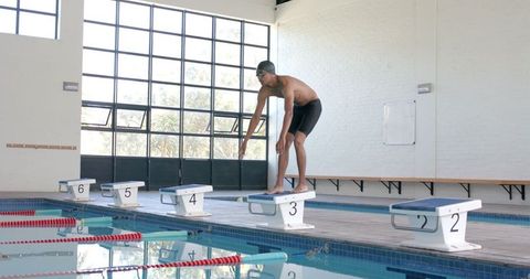 Athletic Swimmer Prepares to Dive at Indoor Pool in Slow Motion