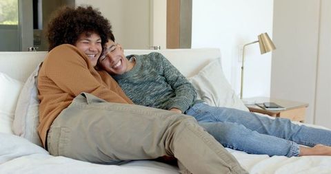 Smiling couple relaxing on bed with tablet in modern bedroom