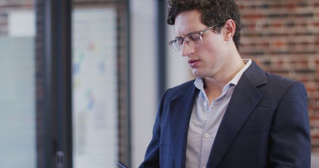 Businessman Wearing Blazer Focusing on Smartphone Screen in Modern Office - Download Free Stock Images Pikwizard.com