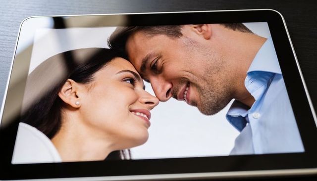 Couple touching foreheads on tablet screen representing remote connection and romance