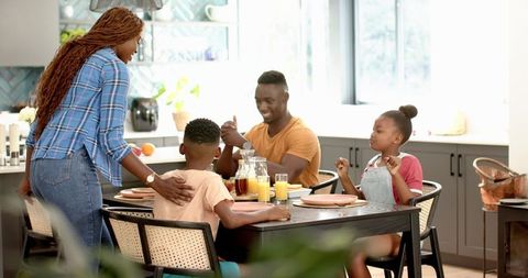 Mother Serving Lunch to Excited Children at Kitchen Table