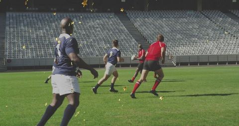 Rugby players running on stadium field chasing ball with dynamic teamwork motion now
