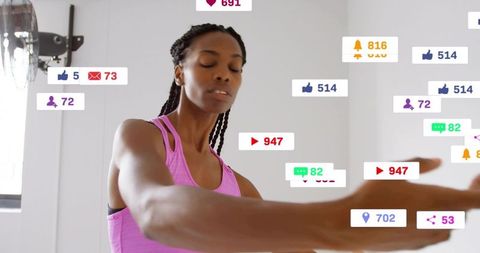 Female trainer stretching in pink tank during live workout with floating social icons
