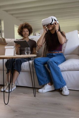 Two african women experiencing virtual reality at home while using tablet for collaboration