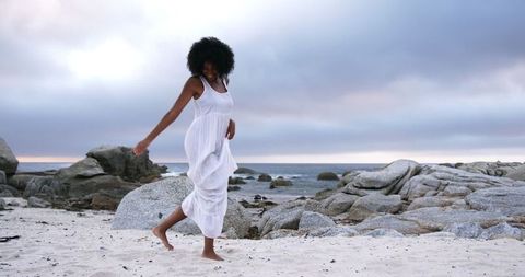 Joyful Young Woman Enjoying a Beach Dance at Sunset