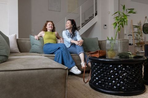 Two friends sitting and chatting on sectional sofa in modern apartment living room