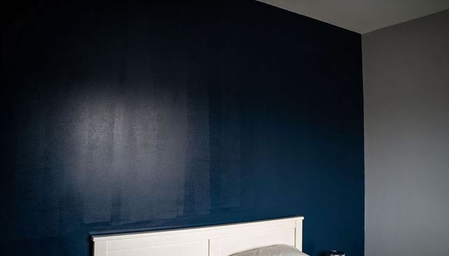 White headboard against deep navy blue feature wall in minimalist modern bedroom corner