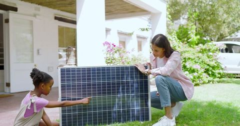 Mother and Daughter Exploring Solar Energy in Green Yard