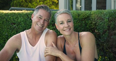 Smiling Senior Couple Relaxing in Garden in Workout Attire