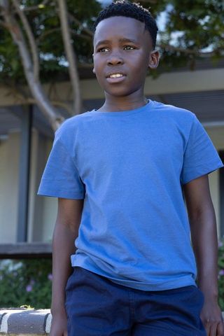 Confident african american boy standing outdoors wearing blue t-shirt looking ahead