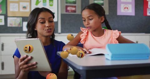 Teacher and student engaged with emoticons on tablet