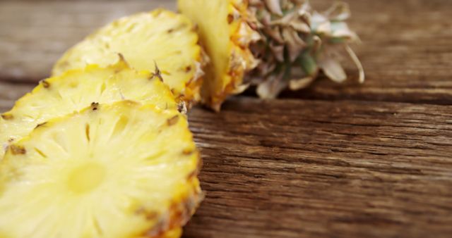 Sliced pineapple rests on a rustic wooden surface, with copy space. Its vibrant yellow flesh and textured rind evoke a sense of tropical freshness and natural sweetness.