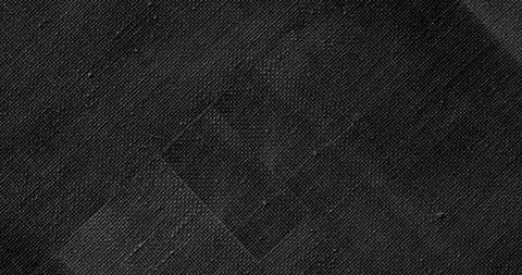 Diagonal stitched square patch on dark woven textile close-up grayscale texture