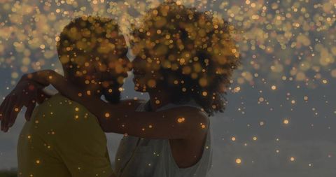 Embracing couple on dusk beach with golden bokeh lights romantic hug warm glow
