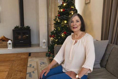 Senior female relaxing at festive home, christmas tree in background