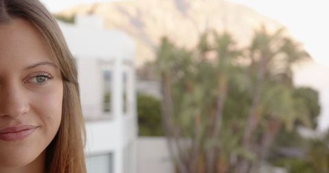 Serene woman on balcony with modern architecture and scenic landscape