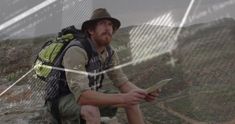 Rugged hiker scanning ridgelines with tablet while planning remote trail navigation routes