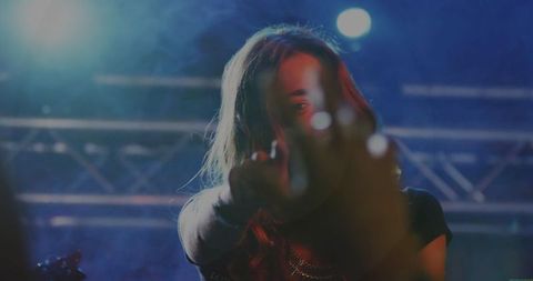 Dynamic female singer reaching towards audience in vibrant concert lighting