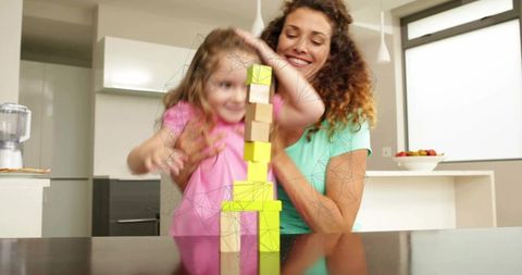 Mother guiding daughter stacking colorful blocks on glossy kitchen counter playful learning
