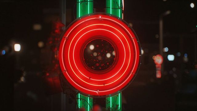 Vibrant neon sign illuminates dusky urban storefront