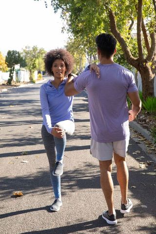 Diverse Couple Stretching Together on Quiet Suburban Street