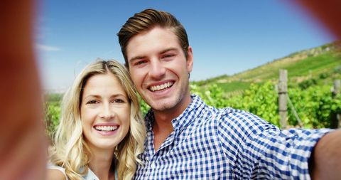 Smiling Couple Taking Selfie in Sunny Vineyard