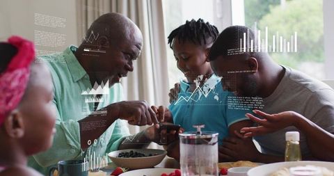 Multigenerational african american family leaning over smartphone viewing data graphs during sunlit