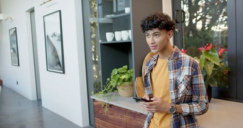 Young Man Leaning in Modern Kitchen Using Smartphone