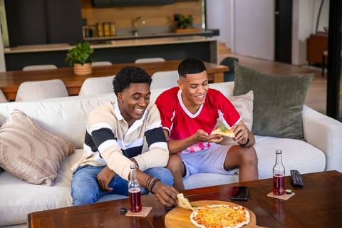 Diverse Friends Enjoying Pizza and Soda in Modern Living Room