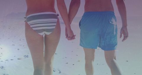 Couple Hand in Hand Strolling on Serene Beach with Vibrant Skies