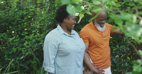 Senior Couple Walking and Smiling in Lush Green Garden