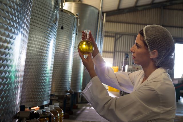 Female technician examining olive oil in factory