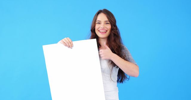 Smiling Woman Holding Blank White Sign Thumbs-up on Blue Background - Download Free Stock Images Pikwizard.com