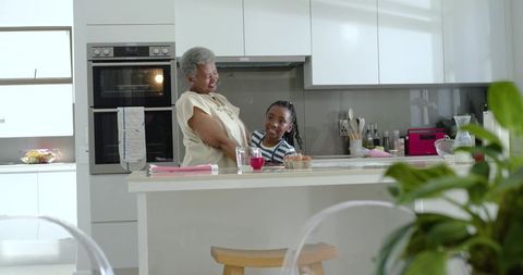 African american grandmother and granddaughter sharing joyful moment in bright kitchen