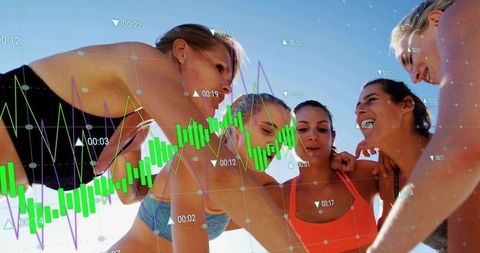 Women huddling on beach with financial charts overlay representing teamwork and growth