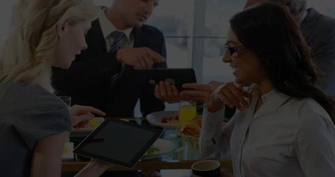 Business team collaborating over tablet during breakfast meeting in modern office lounge