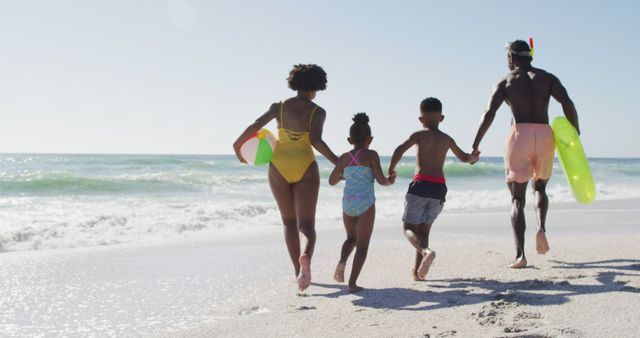 Image of a happy family playing and running on a sandy beach along the ocean shore. Perfect for promoting family vacations, travel destinations, summer holidays, beach resorts, and outdoor activities. Showcases familial bonding, fun in the sun, and relaxation at seaside locations.