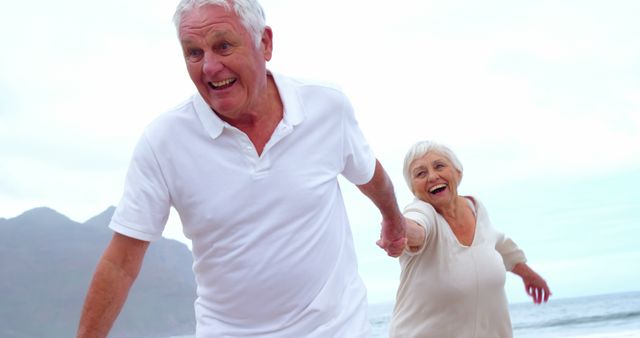 Happy Elderly Couple Holding Hands Running on Beach - Download Free Stock Images Pikwizard.com